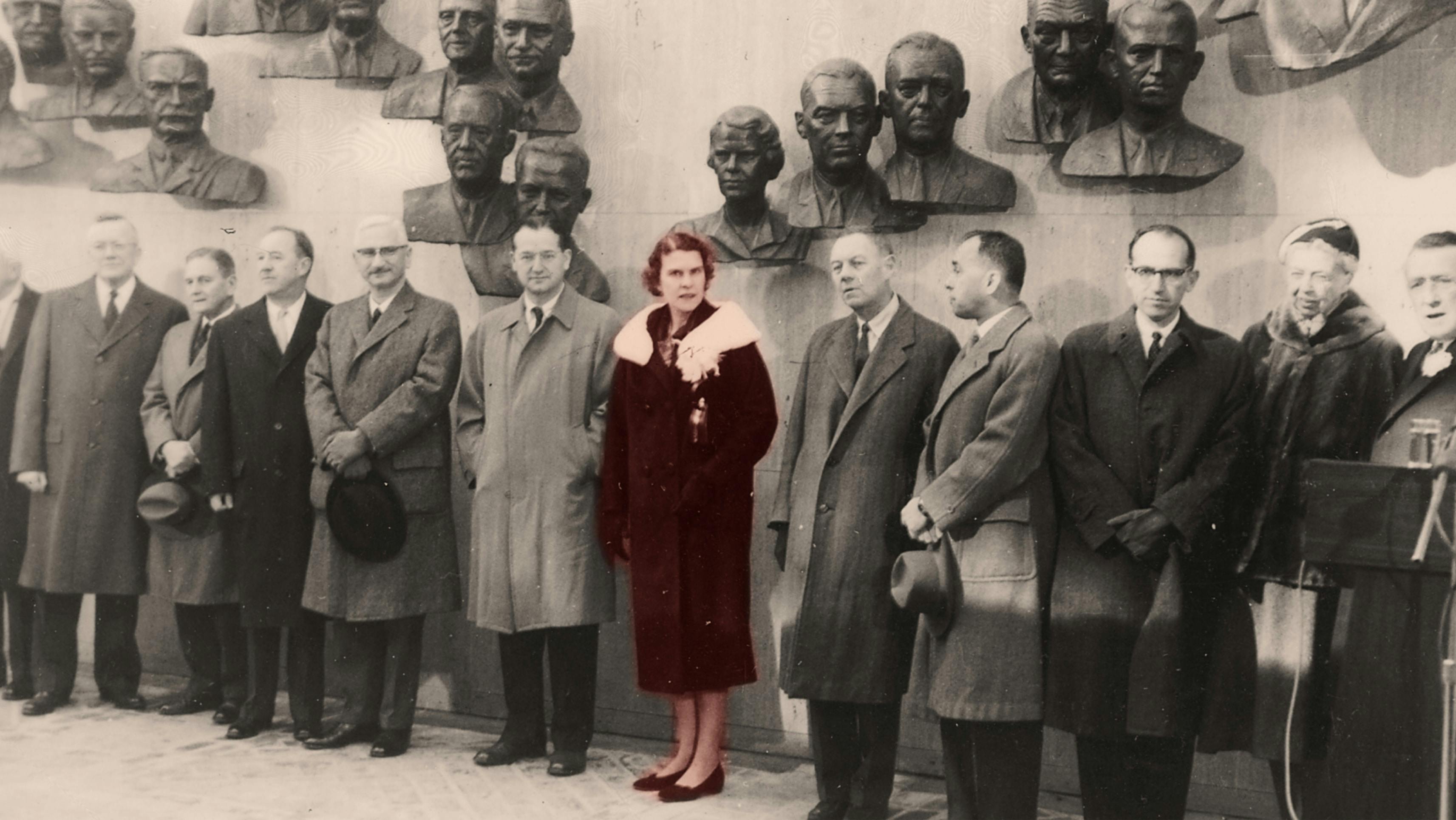 black and white photo of a line of men with a women in the center colorized in red