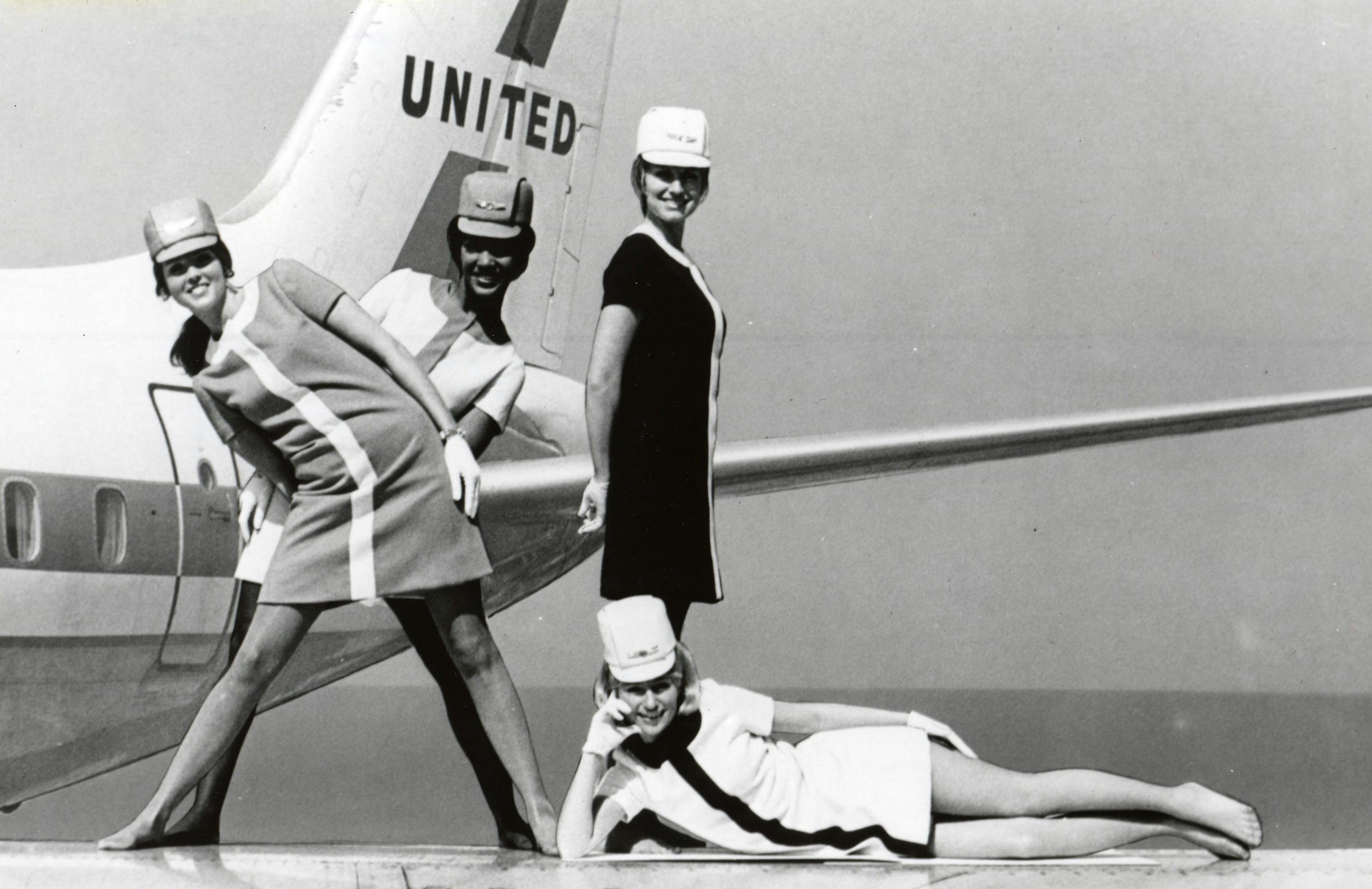 black and white photo of four flight attendants posing in front of an airplane